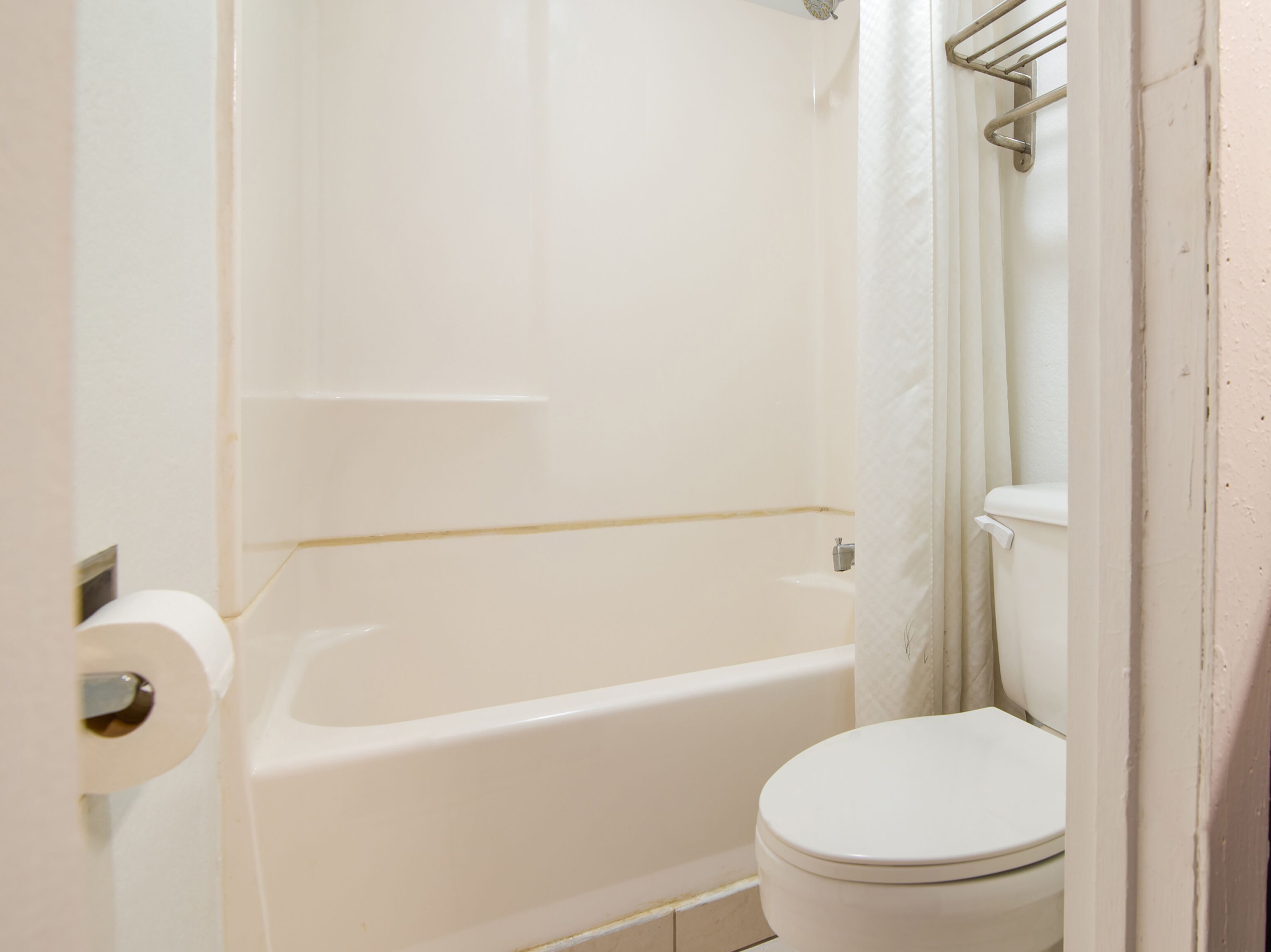 A bathroom with a white bathtub, toilet, and a shower curtain.