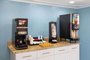 Una estación de café con una máquina de café, un dispensador de agua y un dispensador de bebidas.