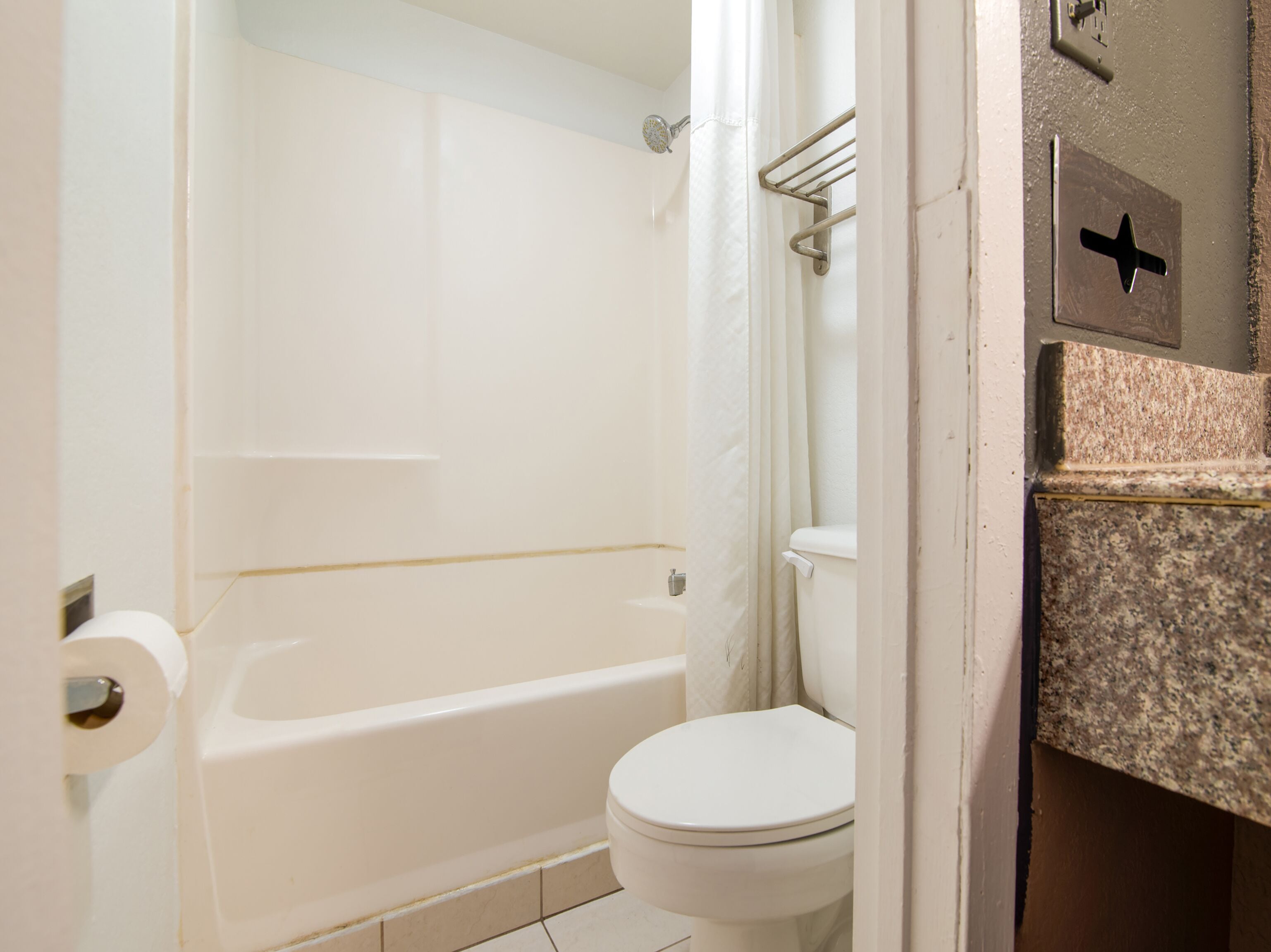 A bathroom with a bathtub, toilet, and shower curtain.