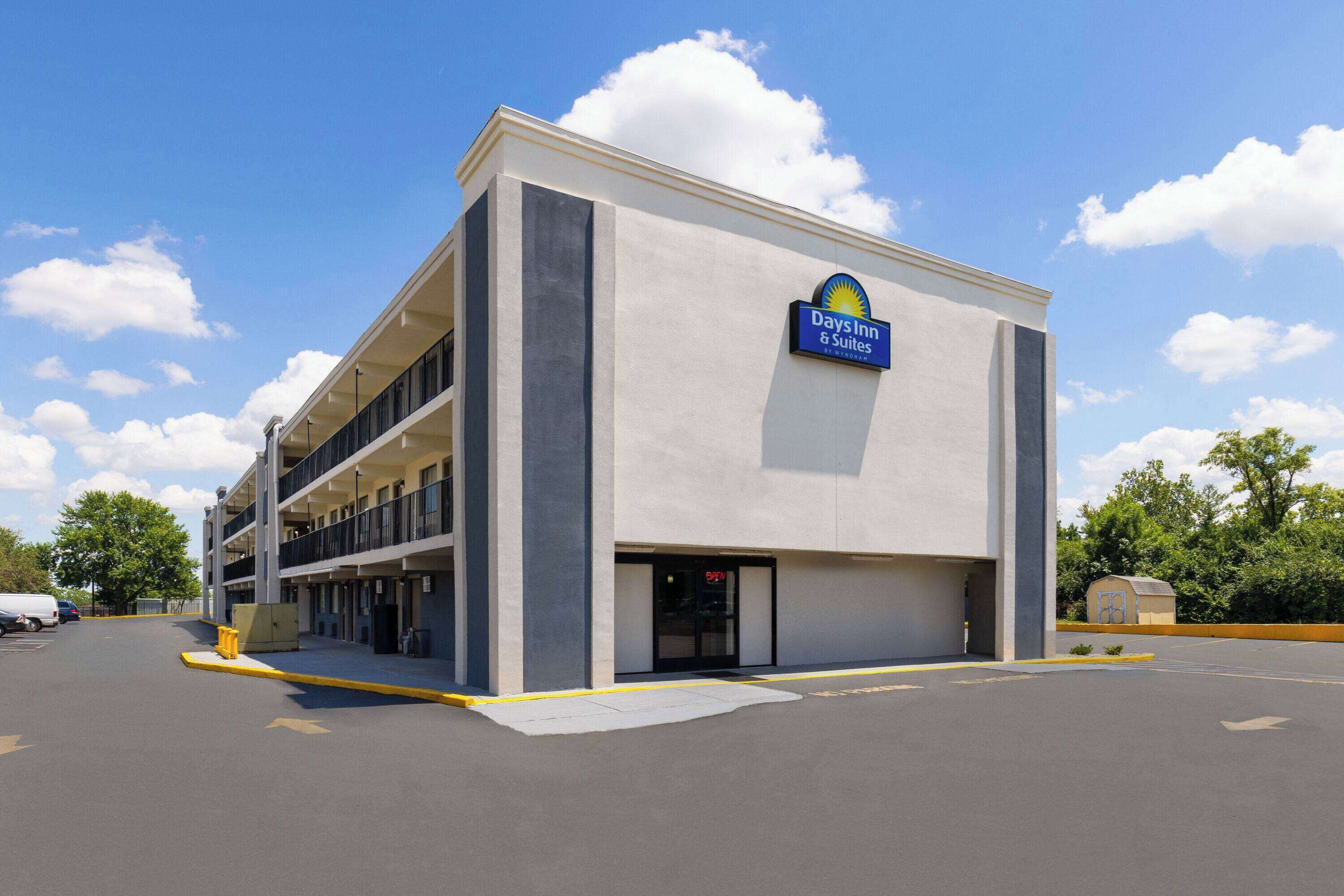 A Days Inn & Suites building with a parking lot and a clear sky.