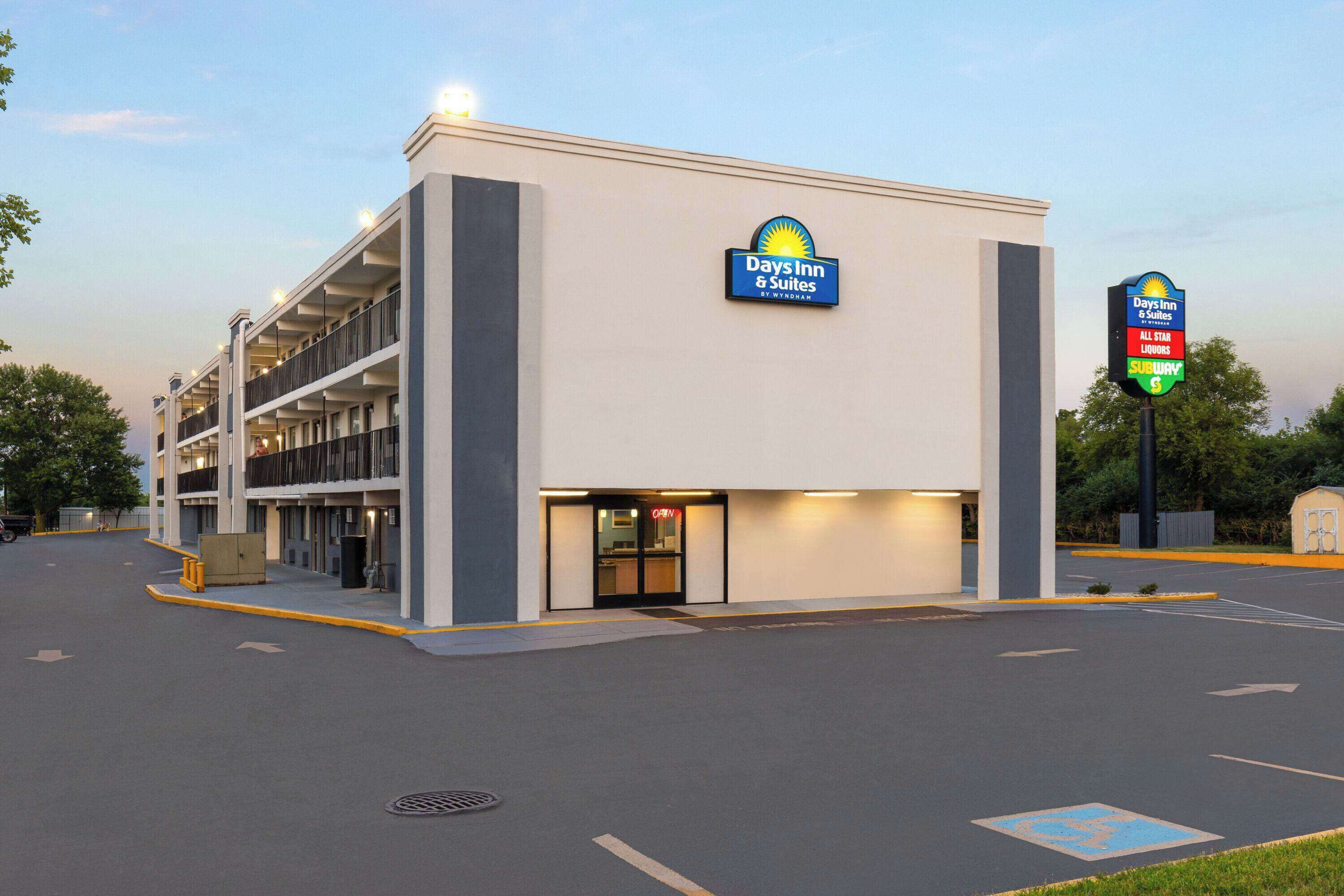 Een Days Inn & Suites hotel met een parkeerplaats en een bord dat nabijgelegen voorzieningen aangeeft.