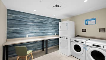 A laundry area with a washing machine, dryer, and a chair.