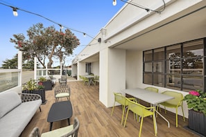 An outdoor seating area with tables and chairs, a wooden floor, and a view of the street. - Hampton Inn San Simeon Cambria (San Simeon)