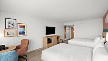 Une chambre d’hôtel avec un lit, un bureau et une chaise, un téléviseur et des tableaux encadrés au mur.