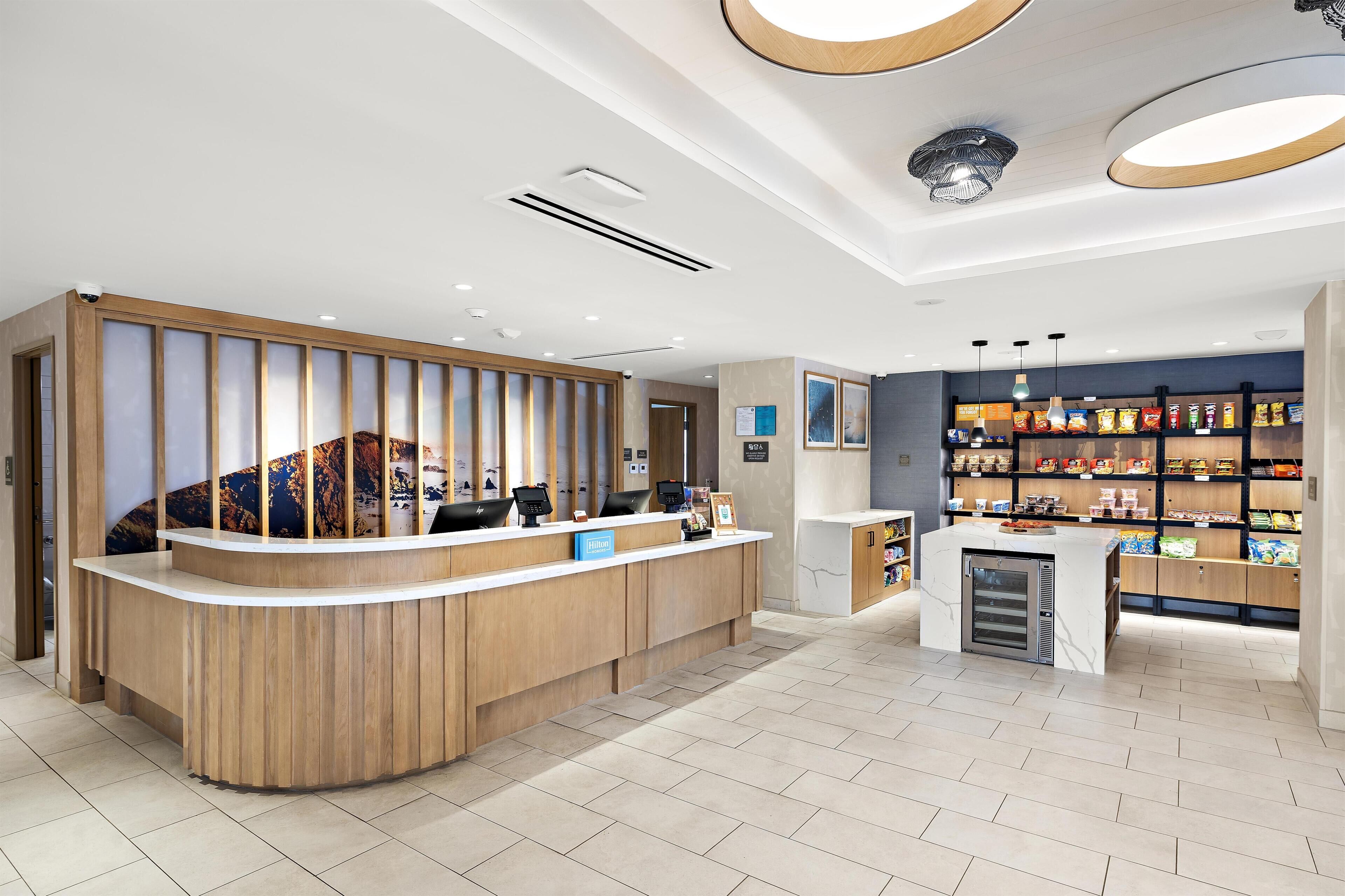Een hotel receptie met een houten balie, een minibar en een snackbar.