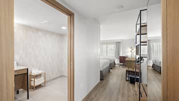 Une chambre d’hôtel avec un lit, un bureau, une chaise et une petite table avec une lampe.