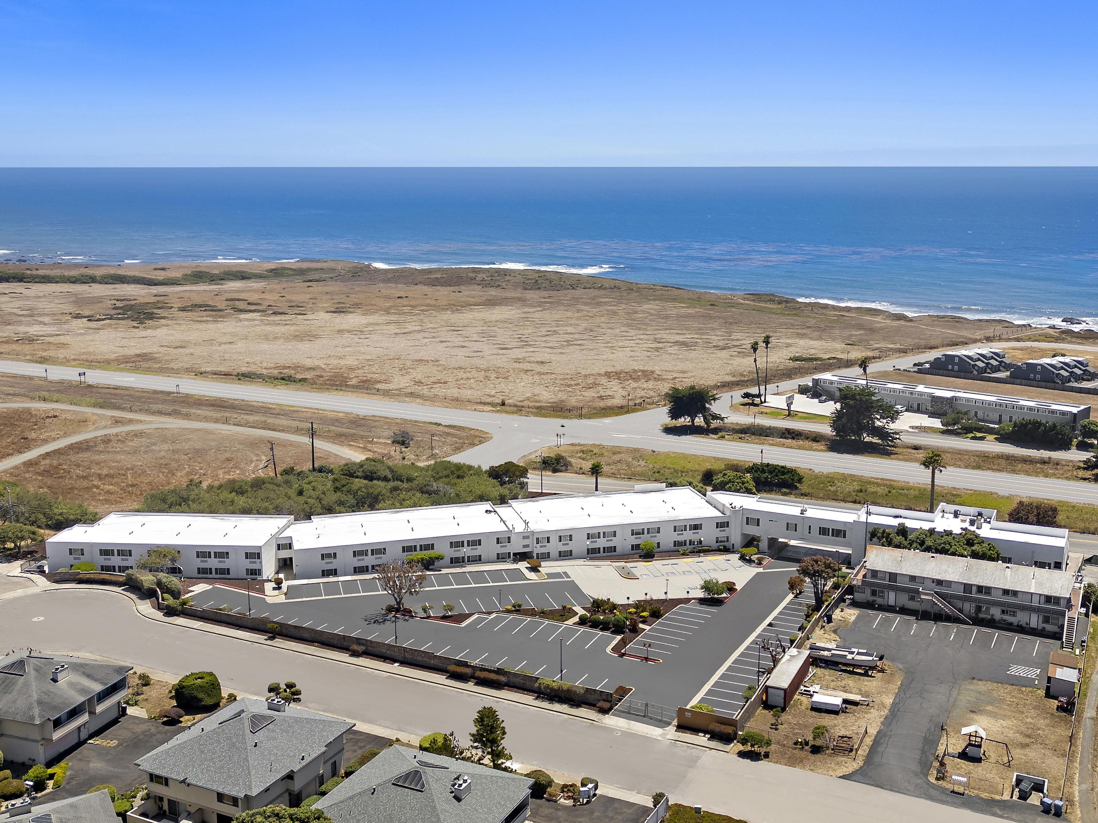 A multi-story building with a parking lot and a view of the ocean.