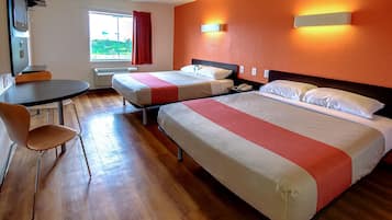 A hotel room with two beds, a desk, and a chair.