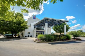 A hotel with a covered entrance, a '6' sign, and a landscaped area with plants and flowers. - Motel 6 King Of Prussia, PA - Philadelphia (Wayne)