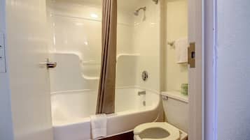 A bathroom with a bathtub, toilet, and shower curtain.