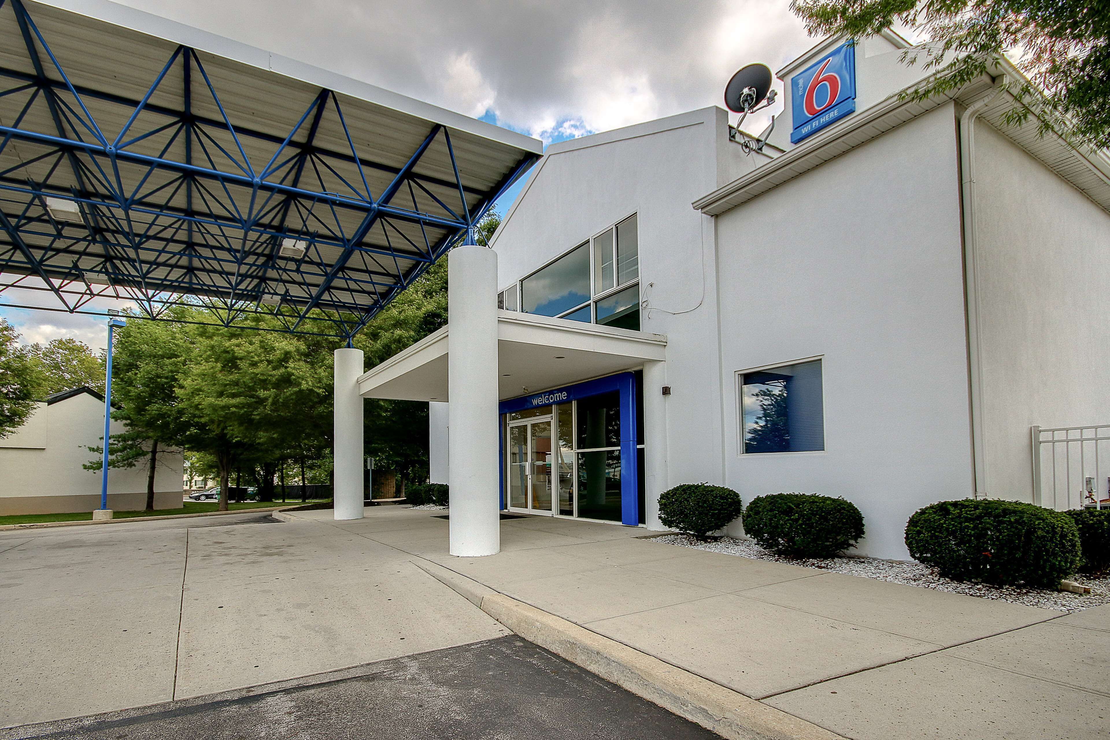 A modern building with a covered entrance, a 'Welcome' sign, and a satellite dish.