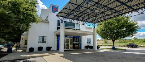 A modern building with a blue entrance and a covered parking area.
