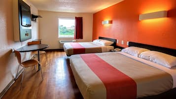 A hotel room with two beds, a desk, a chair, and a TV.