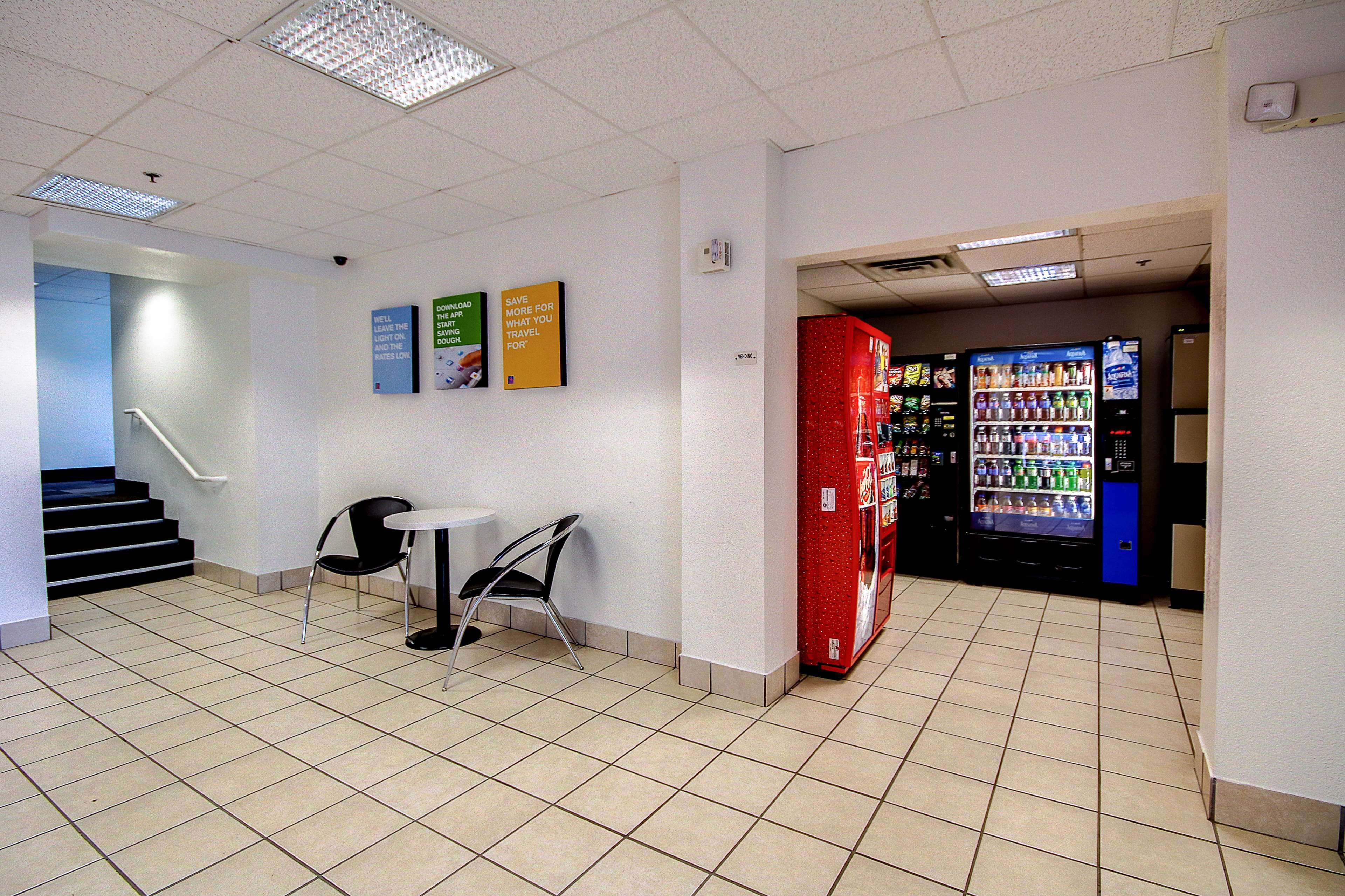 A lobby with a vending machine, a table with chairs, and a staircase.