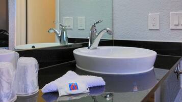 A bathroom with a white sink, a mirror, and a towel on the counter.