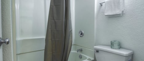 A bathroom with a bathtub, toilet, and shower curtain.