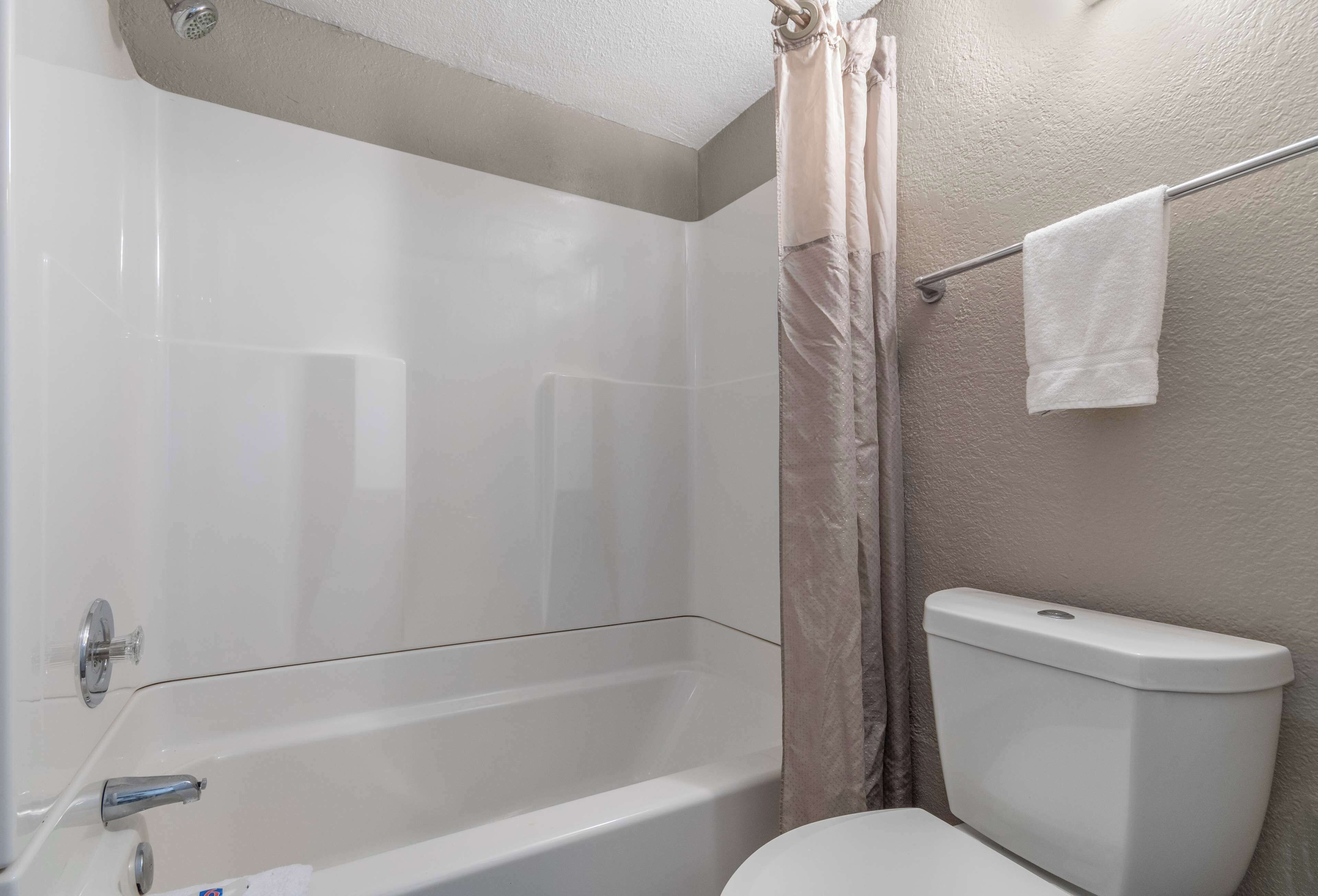 A bathroom with a bathtub, toilet, and shower curtain.