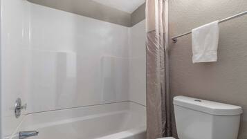 A bathroom with a bathtub, toilet, and shower curtain.