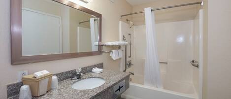 A bathroom with a sink, mirror, shower, and towel rack.
