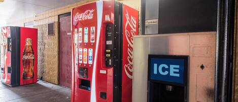 Una fila de máquinas expendedoras, incluyendo Coca-Cola e Ice-O-Matic, en un entorno comercial.