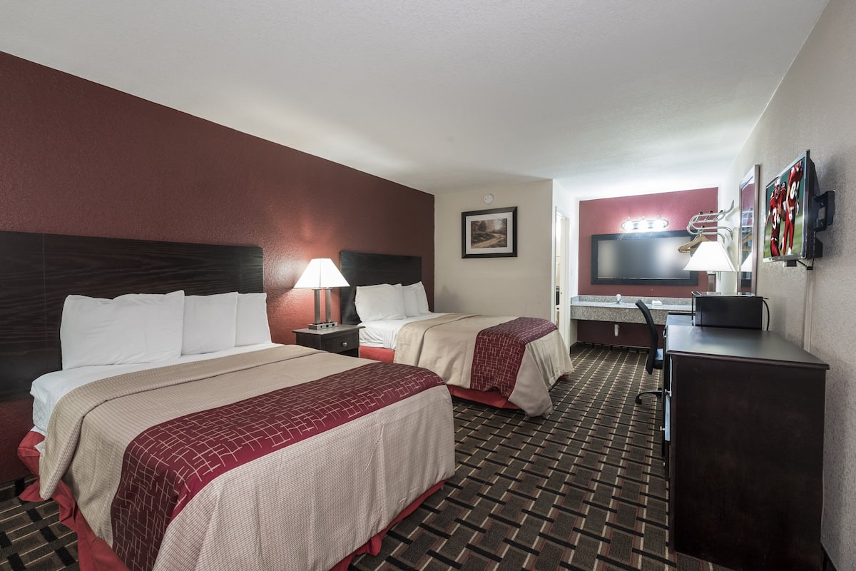 Une chambre d’hôtel avec deux lits, un bureau, une télévision et un miroir.