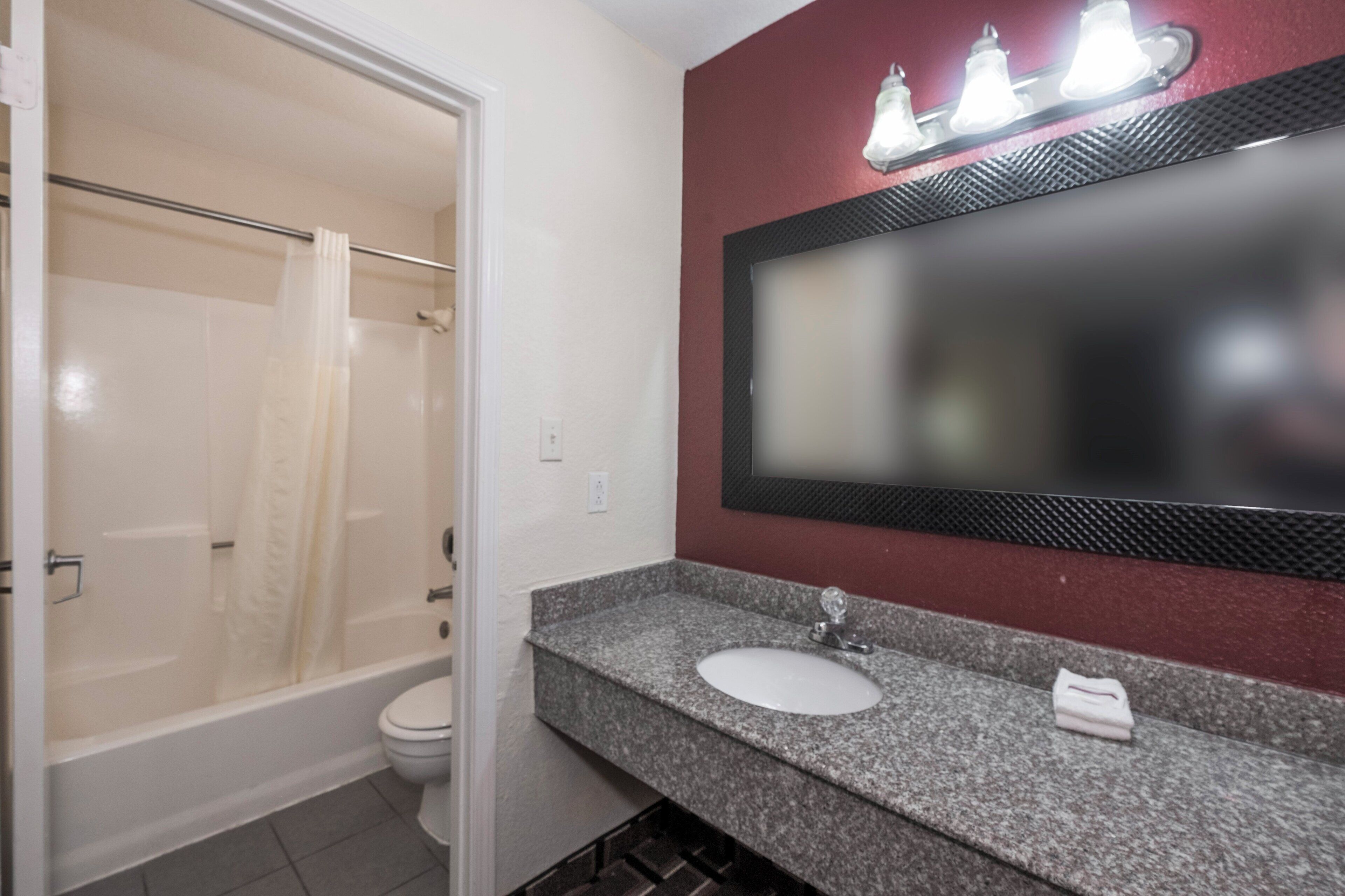 Une salle de bain équipée d’une douche, de toilettes, d’un lavabo et d’un miroir avec des lumières au-dessus.
