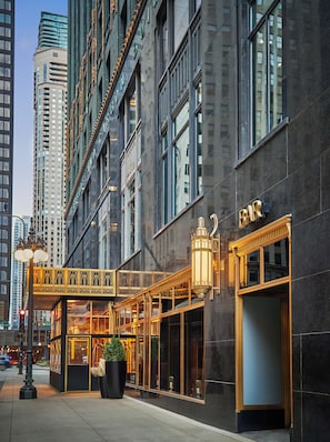 A modern building with a bar on the ground floor, large windows, and a decorative walkway.