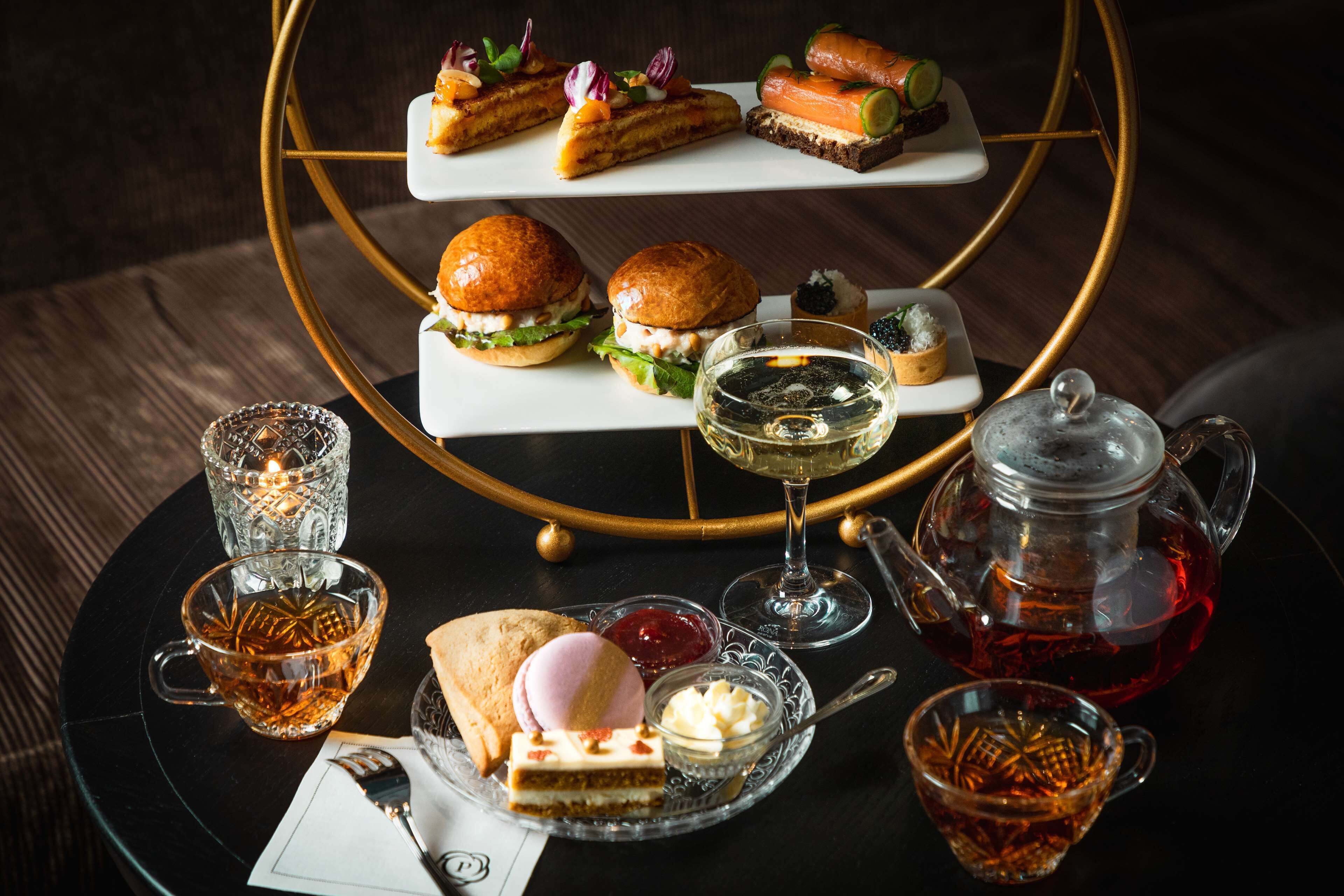 A dessert table with various pastries, sandwiches, and beverages.
