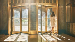 Une porte tournante aux motifs complexes, donnant sur un intérieur bien éclairé et doté d’un plancher poli.