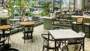 Un café intérieur avec des tables et des chaises, de grandes fenêtres et une vue sur le paysage urbain.