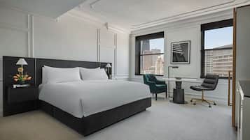 Habitación de hotel moderna con una cama grande, un escritorio, una silla y vistas a la ciudad.