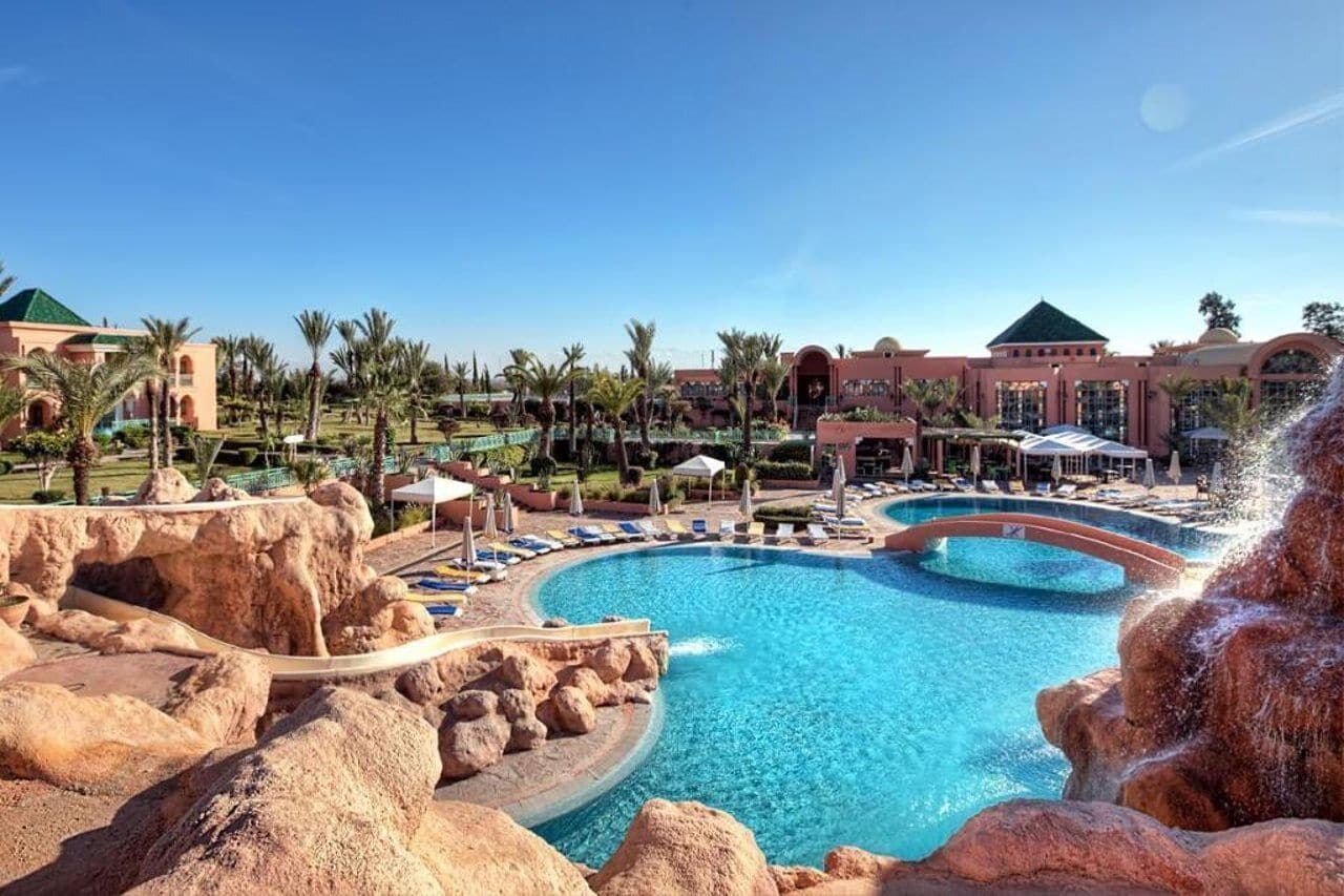 Ein Pool in einem Resort mit kreisförmigem Design, umgeben von Palmen und Resortgebäuden.