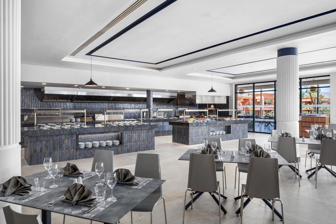 A modern restaurant with a central bar area, dining tables, and chairs.