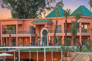 A multi-story hotel with balconies, a central courtyard, and palm trees. - Hotel Marrakech Le Sangho Privilege (Marrakech)