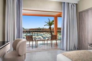A hotel room with a balcony, a desk, a chair, and a view of a pool and resort buildings. - Hotel Marrakech Le Sangho Privilege (Marrakech)