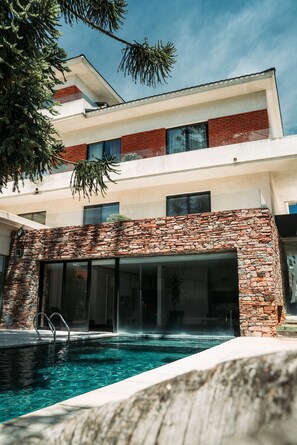 A modern building with a swimming pool, stone facade, and large windows.