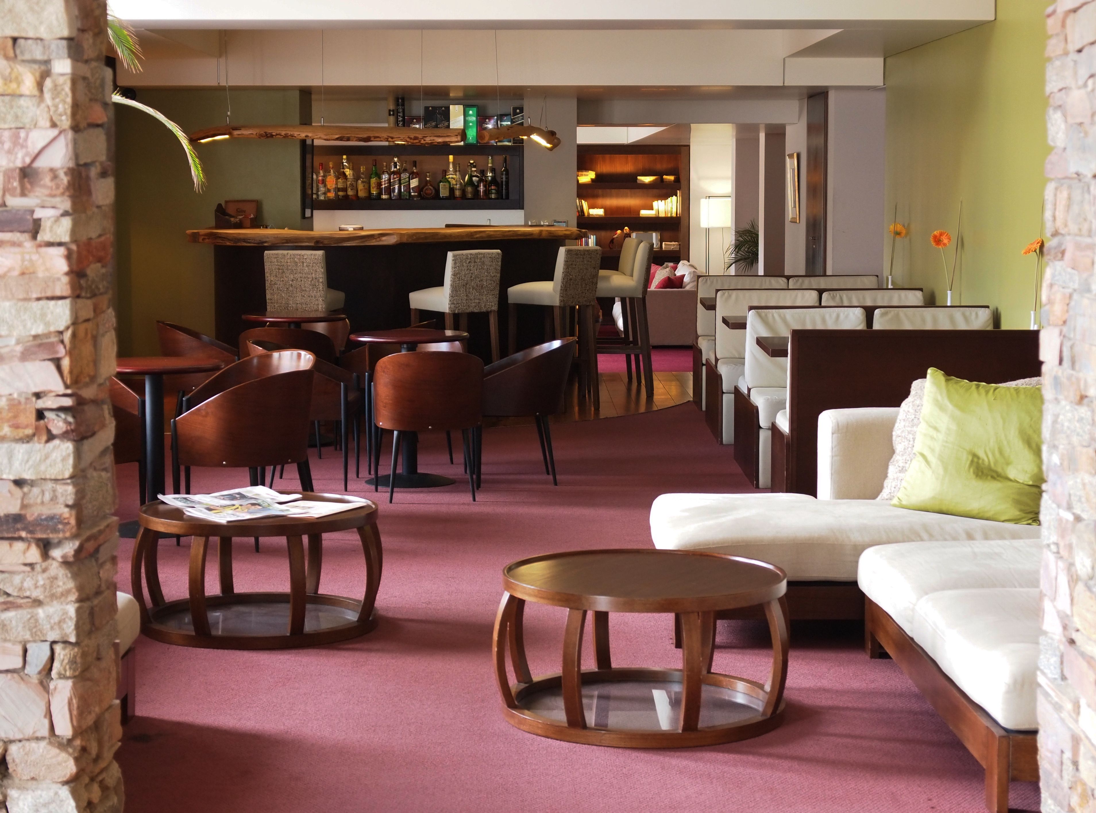 Un área de lounge moderna con un bar, disposición de asientos y una chimenea.