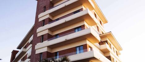 Un hotel de varios pisos con fachada plana, balcones en cada planta y un cartel que indica que es una cabaña hotelera.