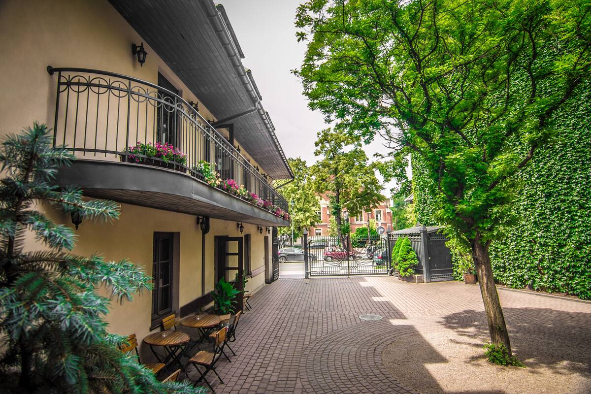 A courtyard with outdoor seating, a tree, and a building with a balcony.