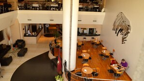 Un vestíbulo de hotel de varios niveles con un atrio central, zonas de estar y una escalera.