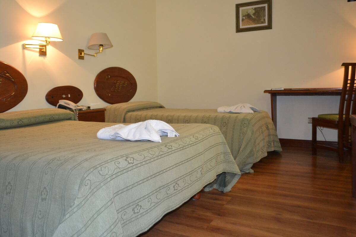 Ein Hotelzimmer mit zwei Betten, einem Schreibtisch und einem Stuhl.