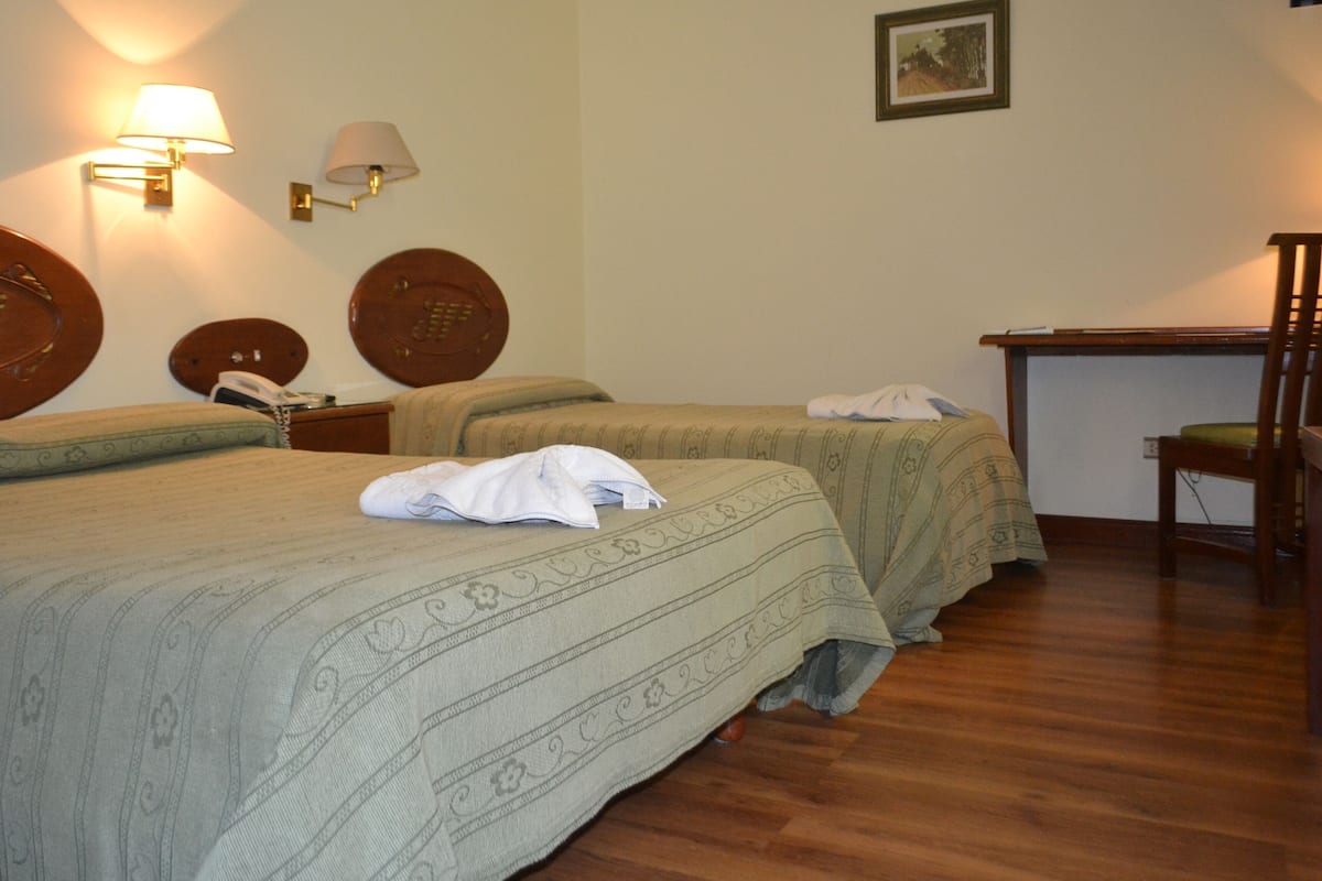 Habitación de hotel con dos camas, un escritorio y una silla.