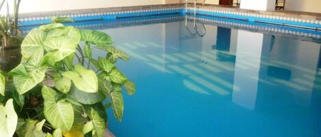 An indoor swimming pool with clear blue water, surrounded by a tiled border.