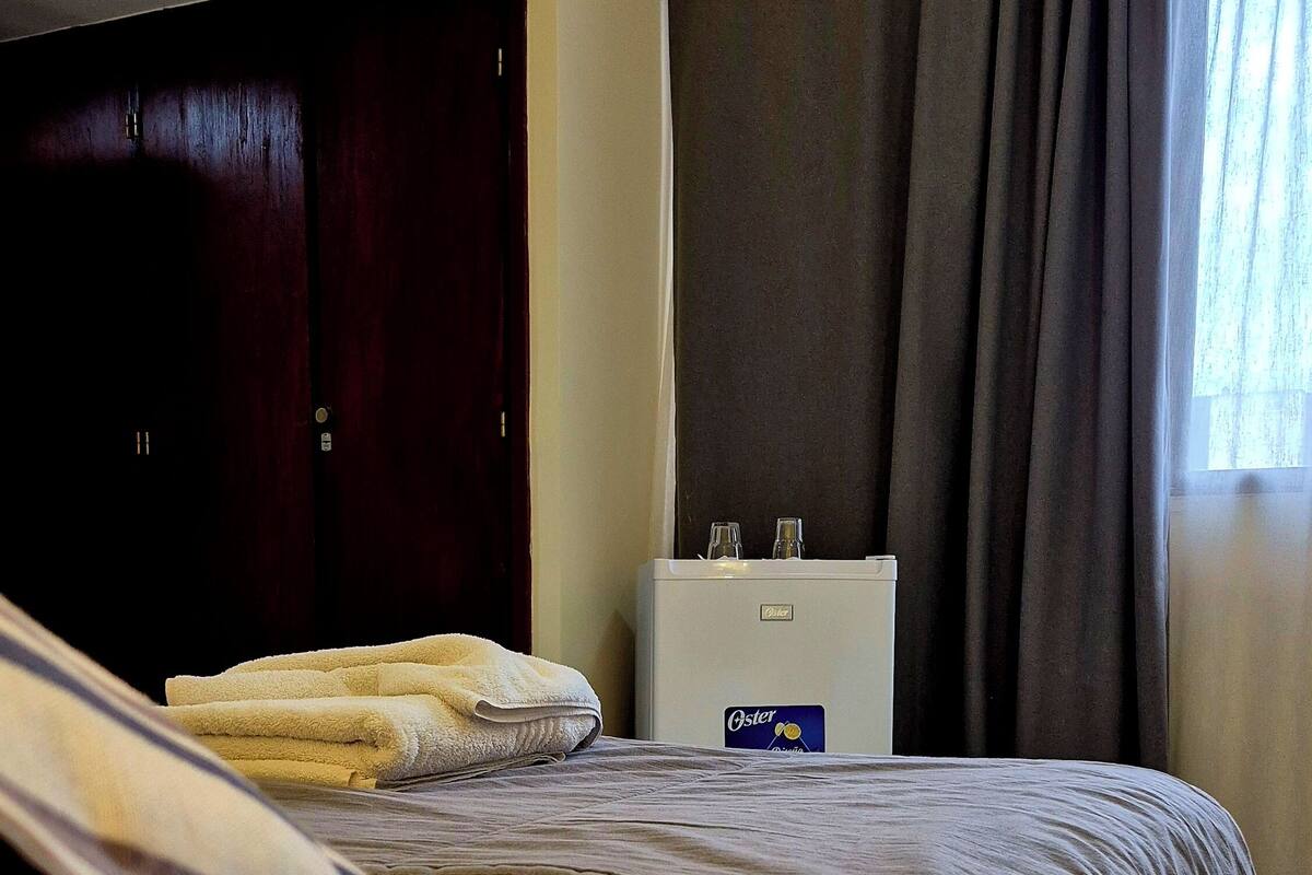 Ein Hotelzimmer mit Bett, Minibar und einem fenster mit Vorhängen.