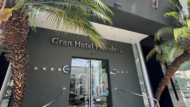 Exterior del Gran Hotel Presidente, con fachada moderna, palmeras y banderas.