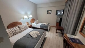 Habitación de hotel con dos camas, un escritorio, un televisor y un cuadro en la pared.