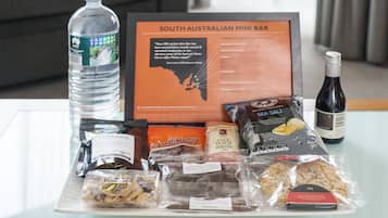 Una mesa con un cartel del Mini Bar australiano Meridional, una botella de agua, aperitivos y una botella de vino.