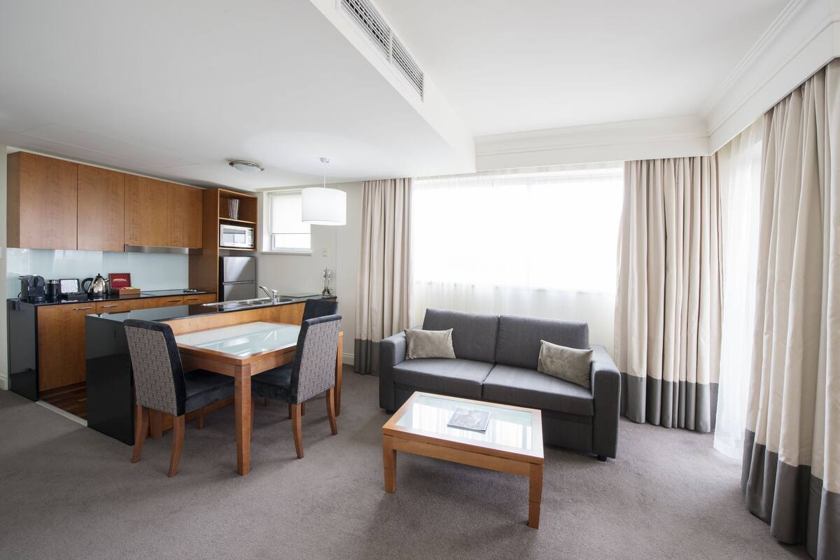 Una habitación de hotel moderna con comedor, sofá y mesa de centro.