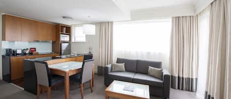 Une chambre d’hôtel moderne dotée d’un coin repas, d’un canapé et d’une table basse.
