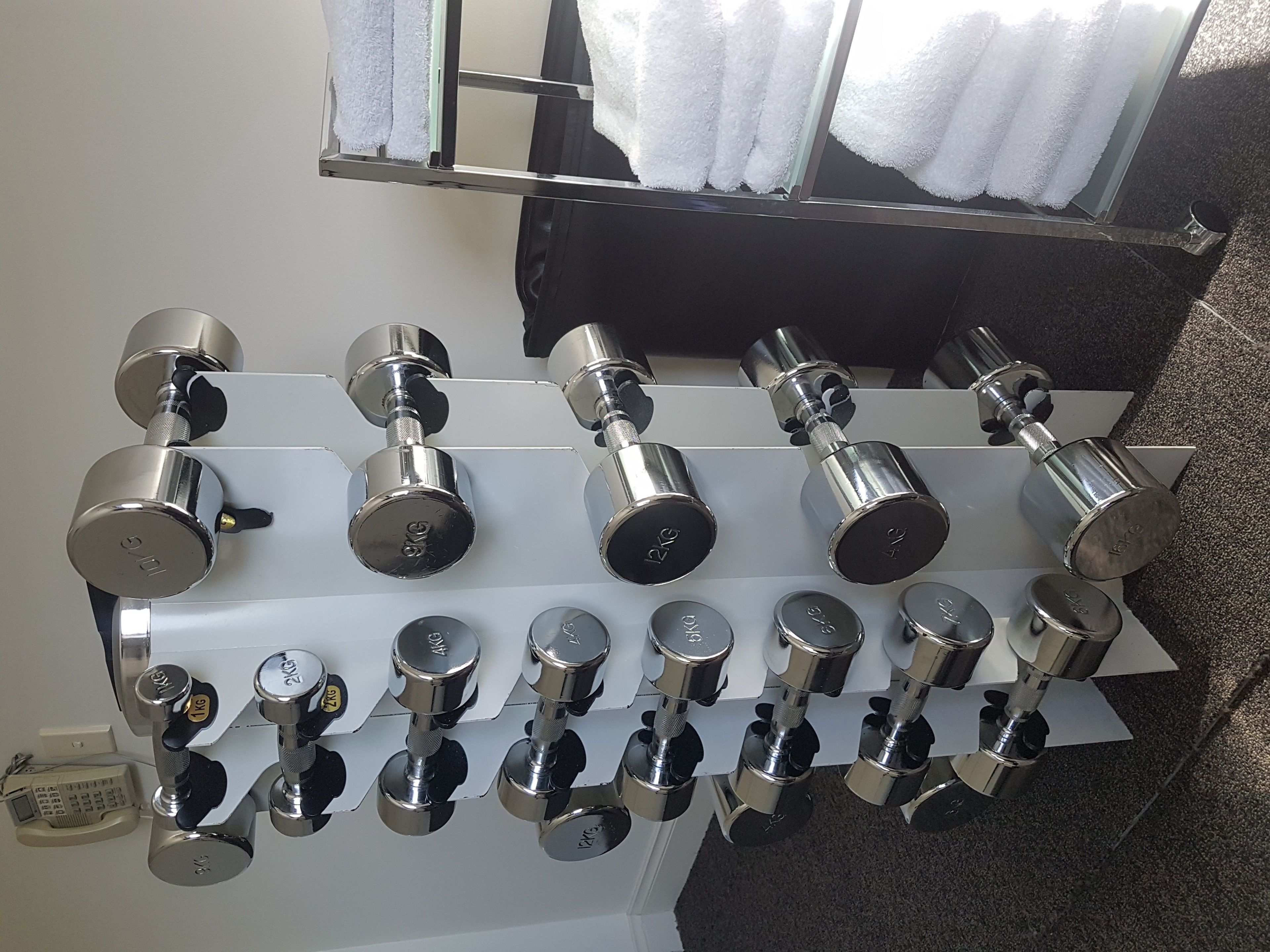 A wall-mounted rack with multiple dumbbells of varying weights.